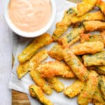 The zucchini fritte are on a cutting board with dipping sauce