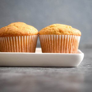 Two vanilla muffins are on a platter.