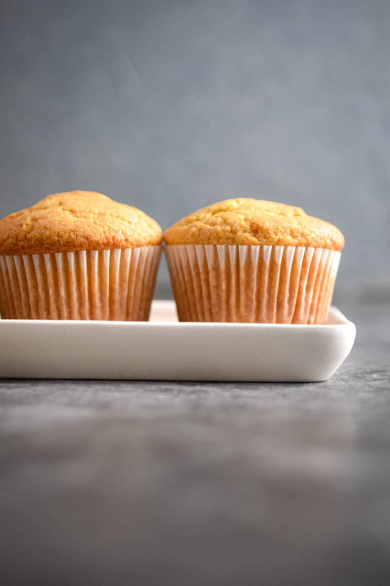 Two vanilla muffins are on a platter.