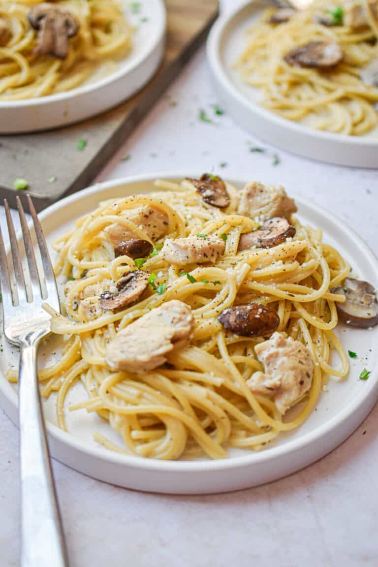 The chicken and mushrooms are surrounding by the spaghetti on a plate of Instant Pot Chicken Tetrazzini.
