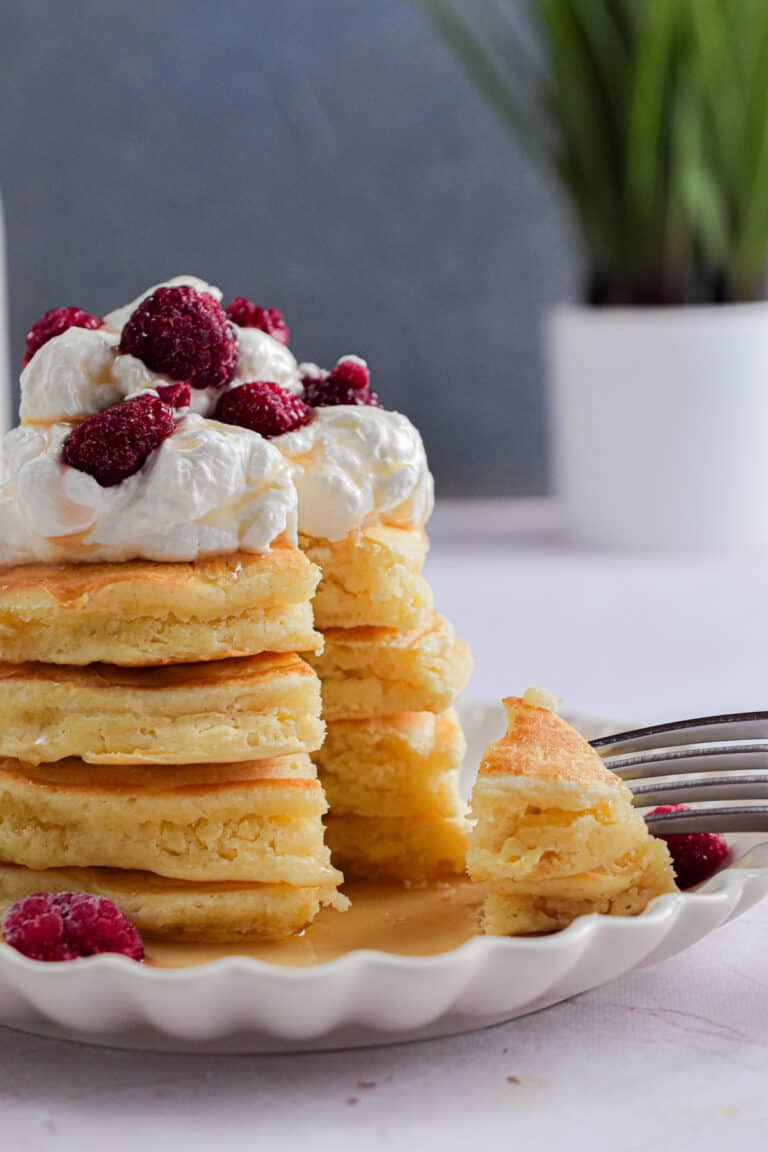 A fork is holding a piece of the stack of pancakes with self-rising flour.