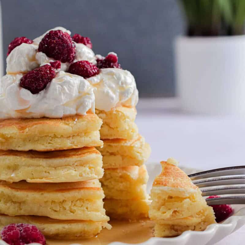 A fork is holding a piece of the stack of pancakes with self-rising flour.