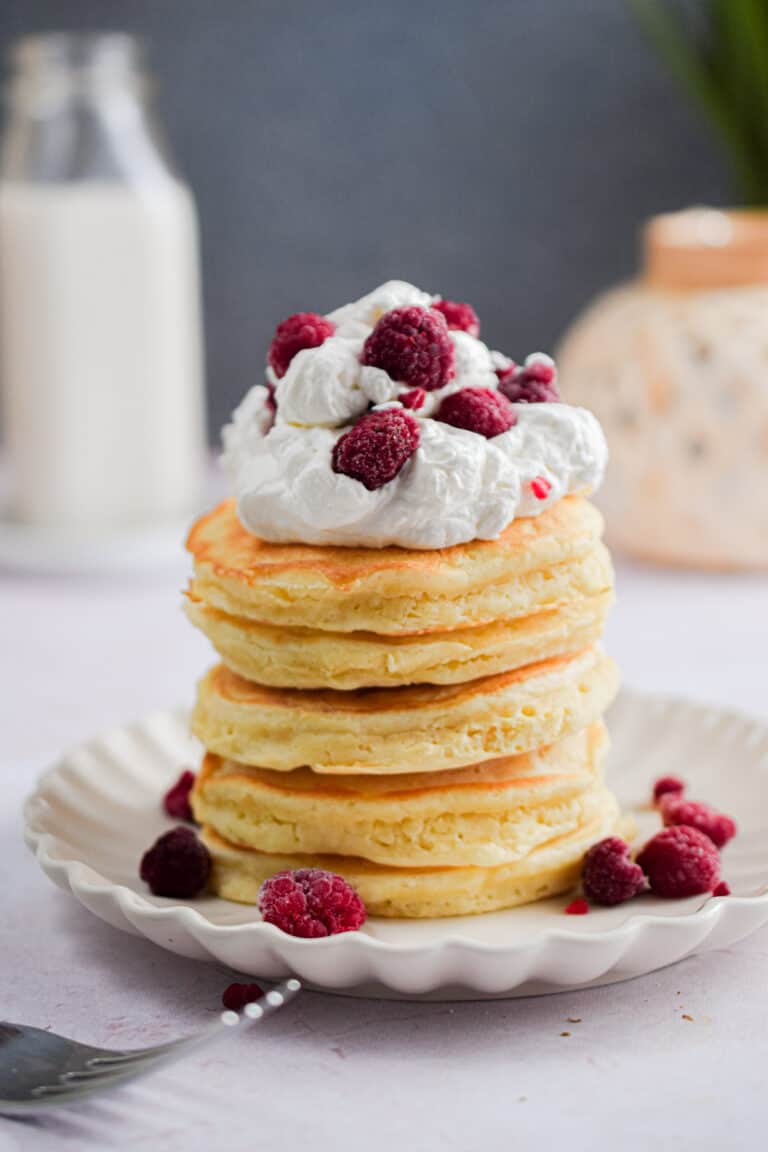 Whipped cream and raspberries are atop the pancakes with self-rising flour stack.