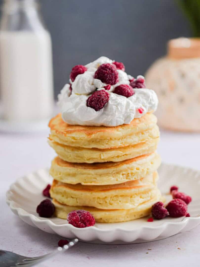 Whipped cream and raspberries are atop the pancakes with self-rising flour stack.