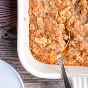 A spoon is in the sweet potato casserole with walnuts