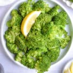 An overhead shot of the instant pot steamed broccoli on a plate with a lemon slice on the plate