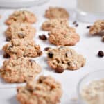 Sourdough oatmeal raisin cookies are in a line with a glass of milk in the background.