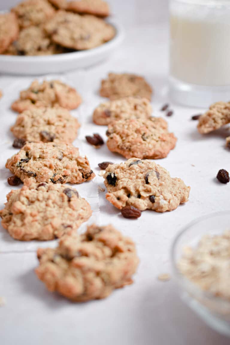 Sourdough oatmeal raisin cookies are in a line with a glass of milk in the background.