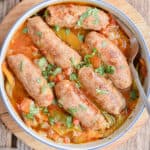Instant Pot sausage and peppers are in a bowl surrounded by peppers