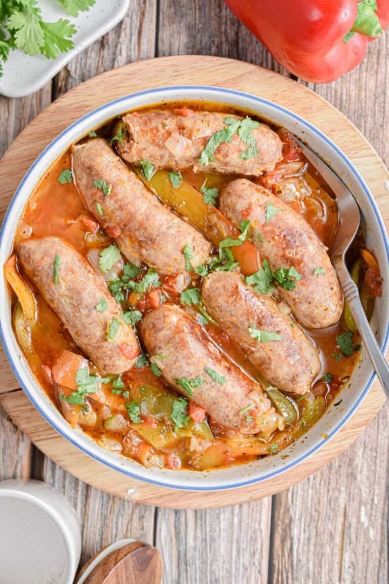 Instant Pot sausage and peppers are in a bowl surrounded by peppers