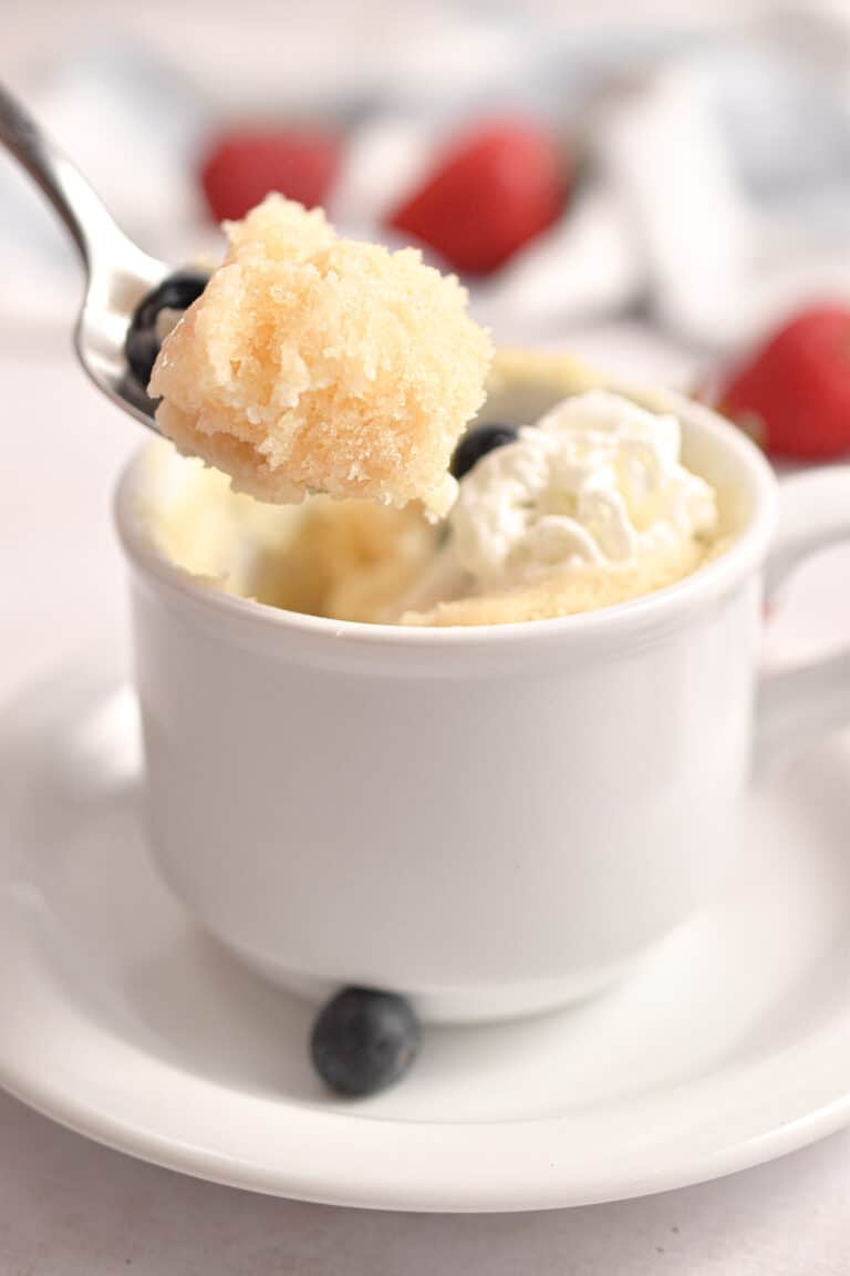 The spoon is lifting the pancake in a mug.