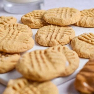 A glass of milk is in the background of the cookies