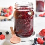A close up of the instant pot mixed berry jam surrounded by fruit.