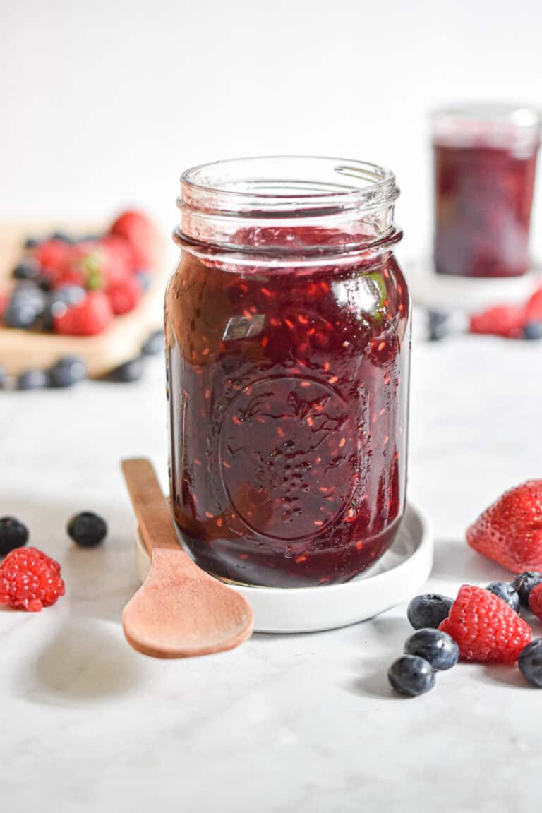 A close up of the instant pot mixed berry jam surrounded by fruit.