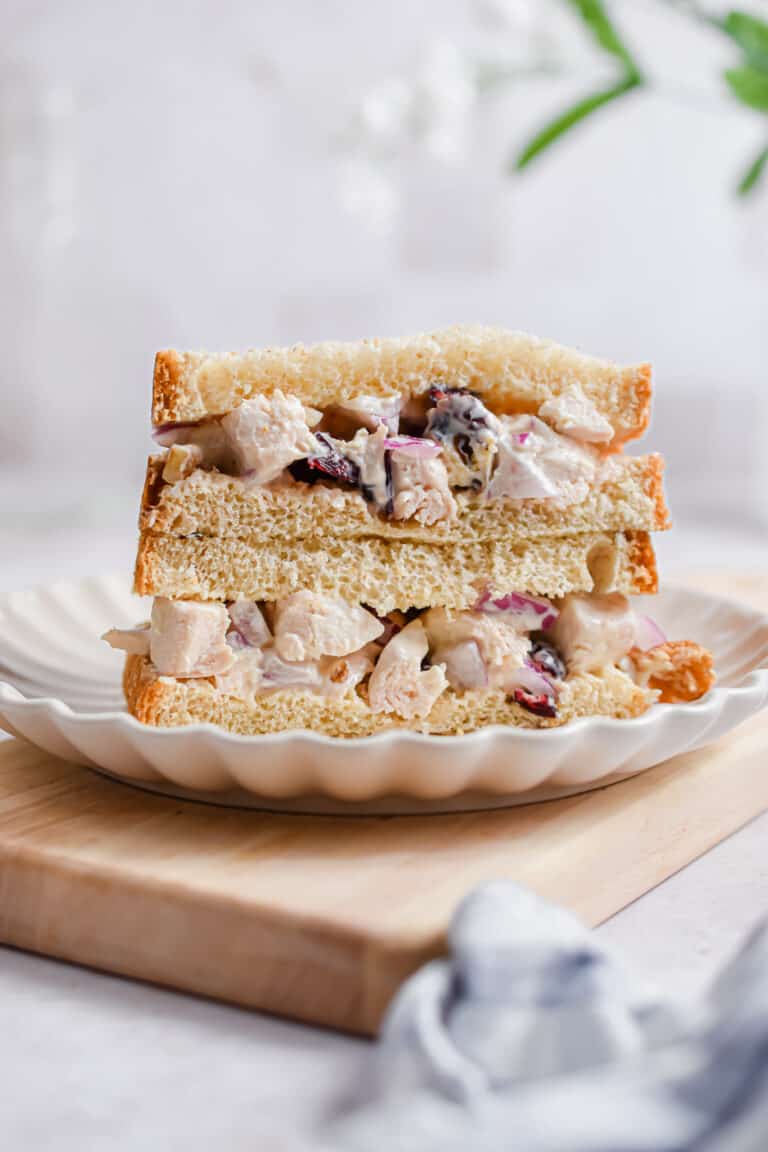 The cranberry walnut chicken salad is being served on bread that is cut in half.