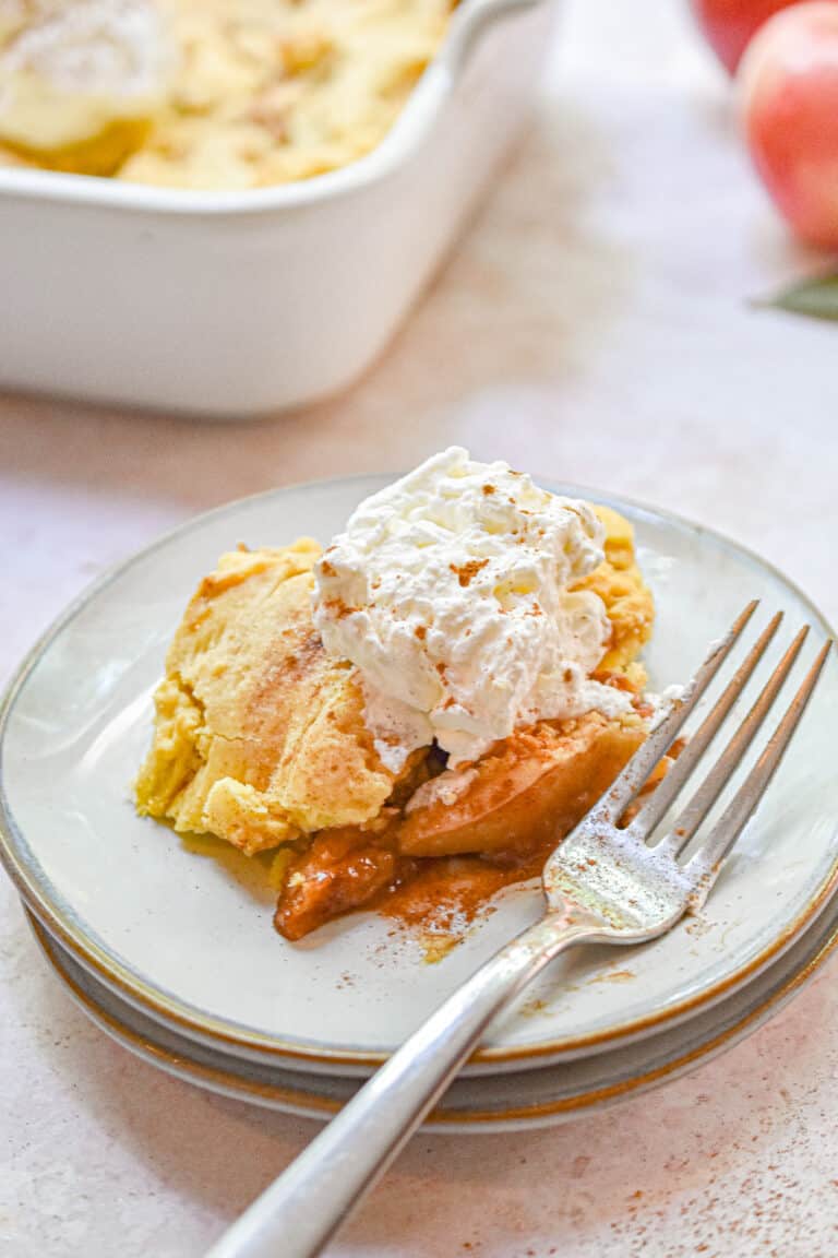 A fork is on the plate with the apple cobbler and whipped cream.