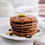 Syrup is dripping off the pancakes with a pat of butter on top of the stack.