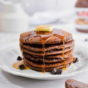 Syrup is dripping off the pancakes with a pat of butter on top of the stack.
