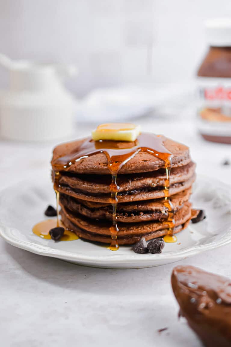Syrup is dripping off the pancakes with a pat of butter on top of the stack.