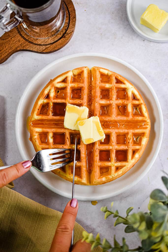 A fork and knife are cutting into the waffle.