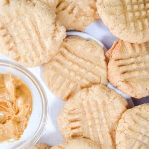 The pancake mix peanut butter cookies are surrounding a bowl of peanut butter.