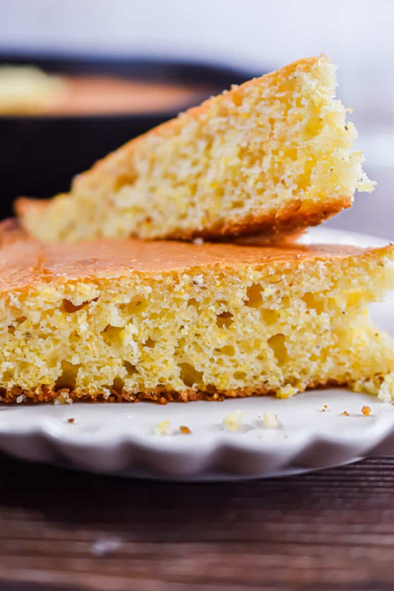 Two pieces of cornbread are on a fluted plate.
