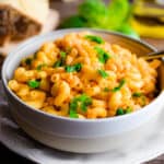 The pasta fagioli is in a bowl surrounded by basil, olive oil, and a yellow napkin.