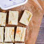The cut cheesecake bars are on a parchment paper with the Farmer's cheese.