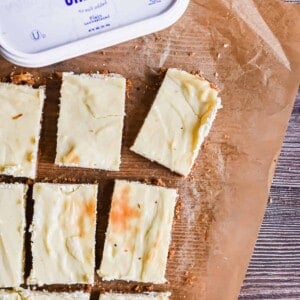 The cut cheesecake bars are on a parchment paper with the Farmer's cheese.