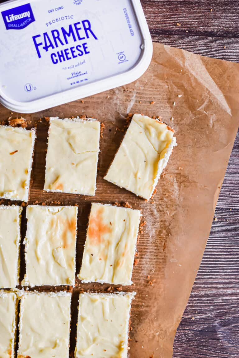 The cut cheesecake bars are on a parchment paper with the Farmer's cheese.