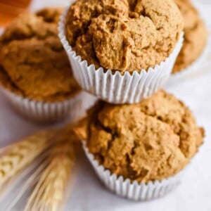 Four muffins are stacked with a piece of wheat underneath the pyramid.