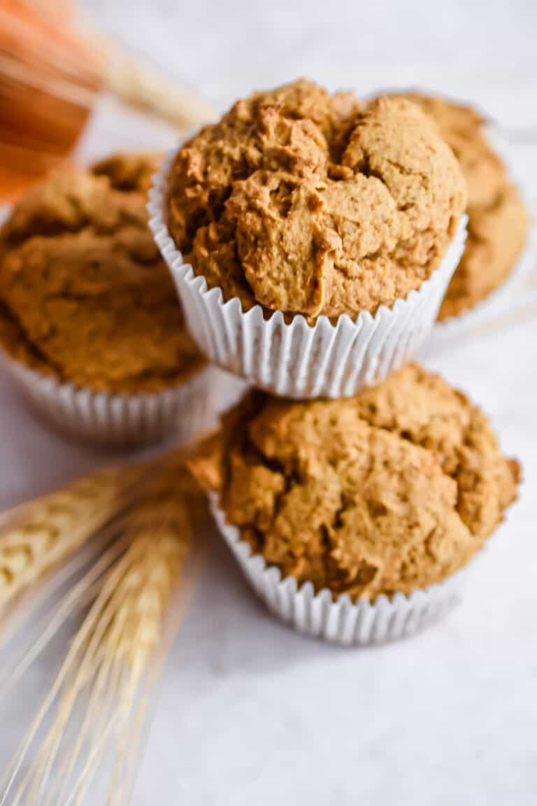 Four muffins are stacked with a piece of wheat underneath the pyramid.