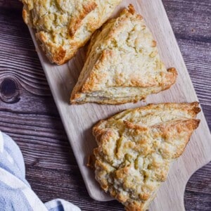Three scones are on a cutting board.