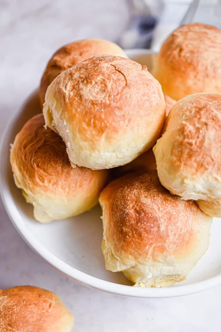 Brioche dinner rolls are piled high on a plate.
