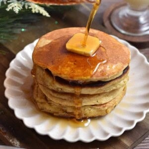Maple syrup is being poured onto a stack of eggnog pancakes.