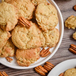 Two plates of coconut pecan cookies are surrounded by pecan halves.