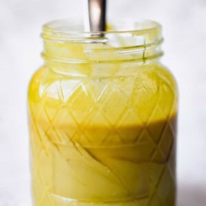 A spoon is sticking out of a mason jar with 2 ingredient honey mustard.