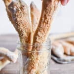 A hand is grabbing a sourdough breadstick.