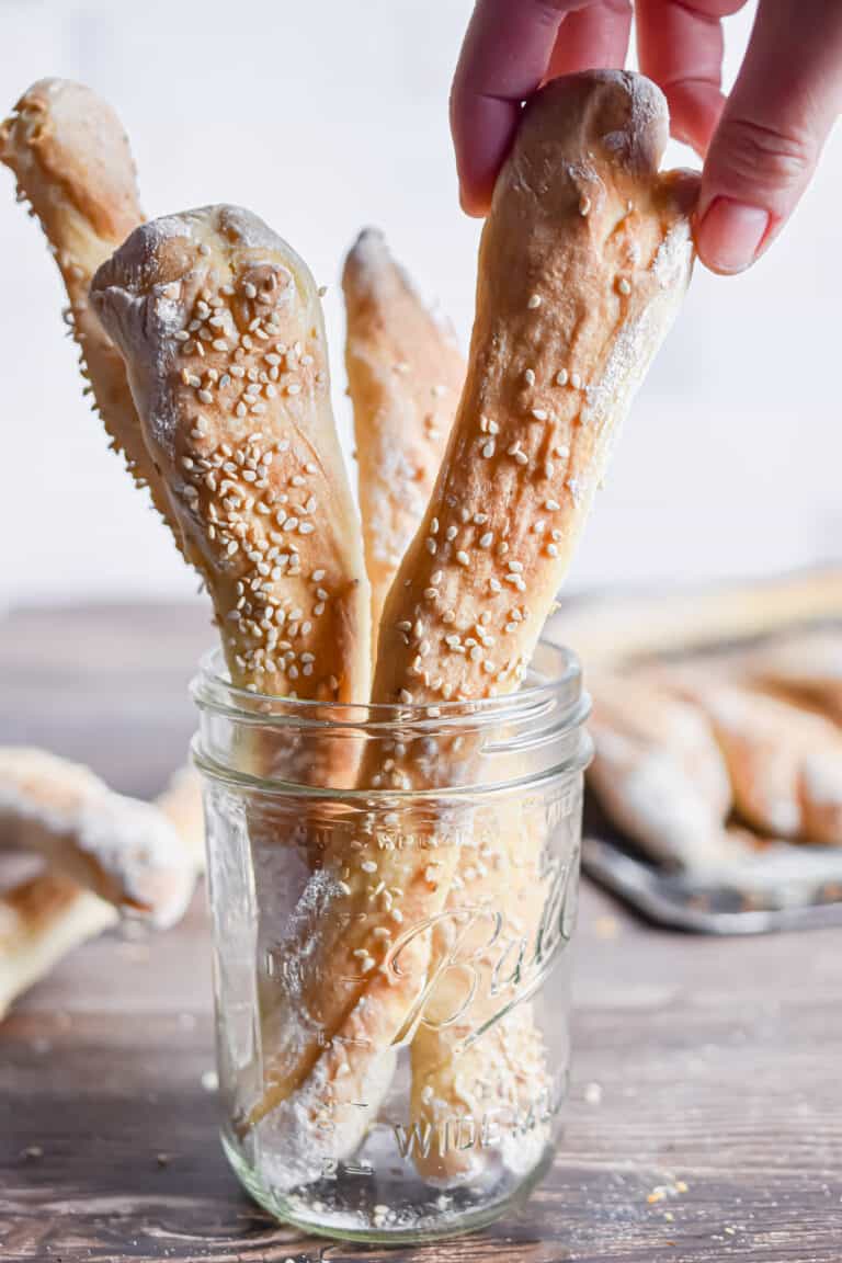 A hand is grabbing a sourdough breadstick.