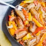 A fork is in the pan with the one pot sausage and peppers and a yellow napkin on the corner of the pan.