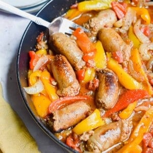 A fork is in the pan with the one pot sausage and peppers and a yellow napkin on the corner of the pan.