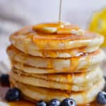 Maple syrup is being poured onto the pancakes.