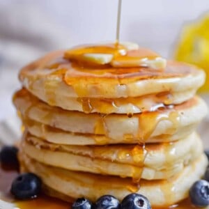 Maple syrup is being poured onto the pancakes.