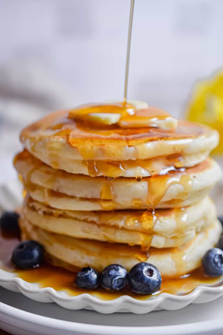 Maple syrup is being poured onto the pancakes.