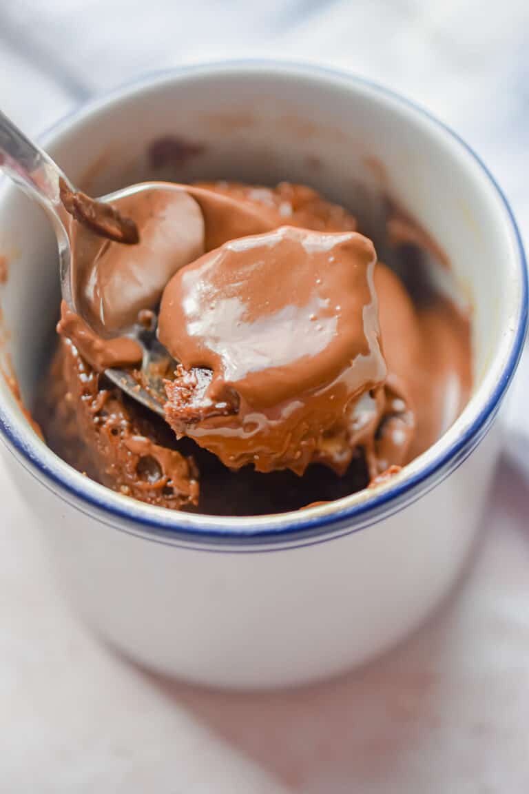 A spoon is lifting the Nutella Mug cake out of the mug.