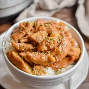 A fork is on the plate under the Instant Pot Bourbon chicken in a bowl.