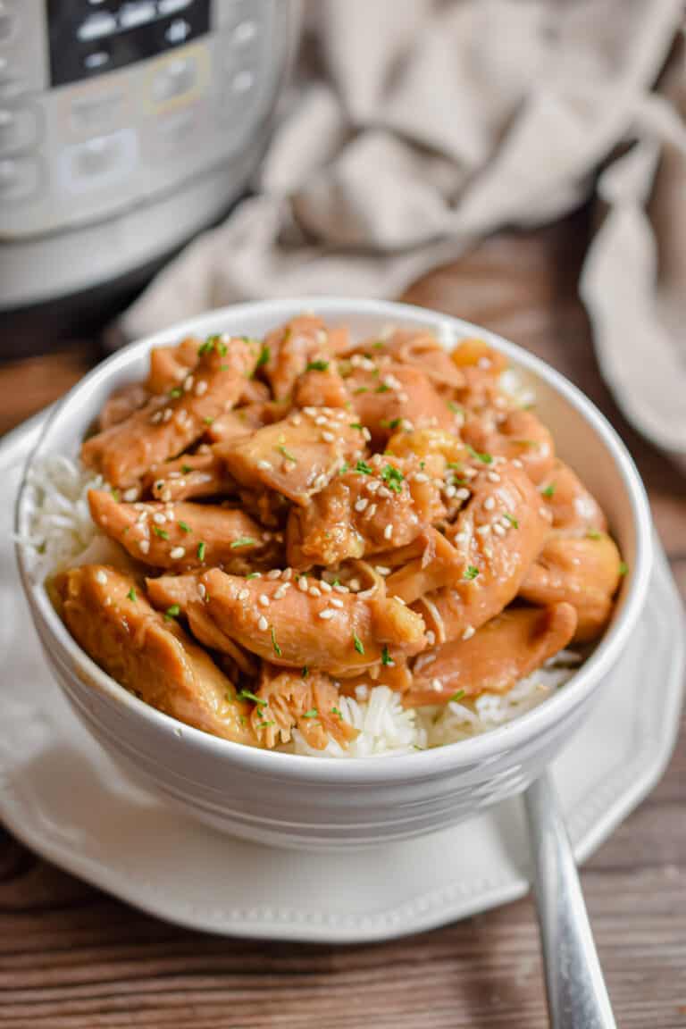 A fork is on the plate under the Instant Pot Bourbon chicken in a bowl.