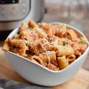A bowl of Instant Pot Rigatoni is in front of the Instant Pot.