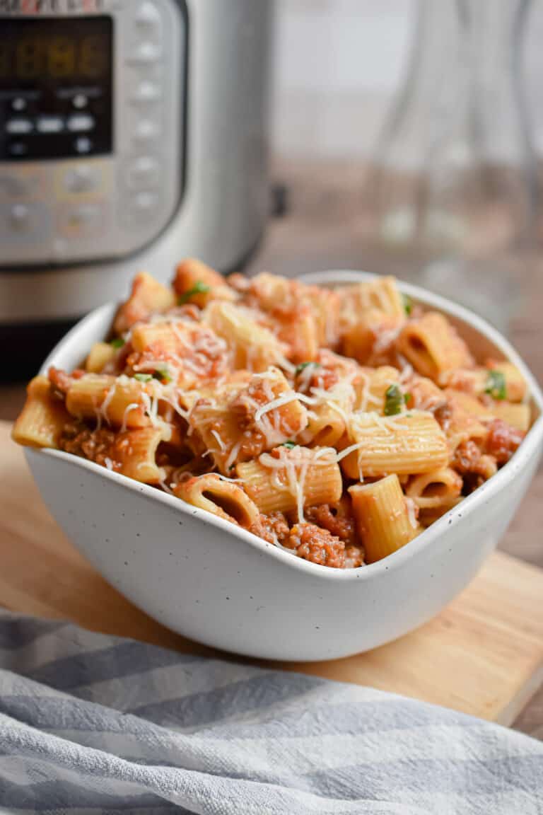 A bowl of Instant Pot Rigatoni is in front of the Instant Pot.