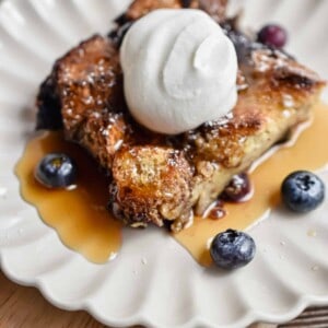 A portion of the french toast blueberry casserole is on a fluted plate.